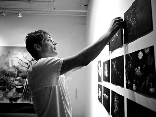 an artist hanging works on paper on his studio wall